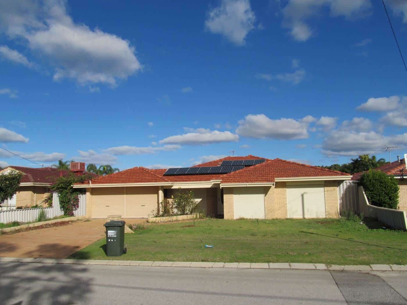 A suburban brick home with solar panels on a tiled roof