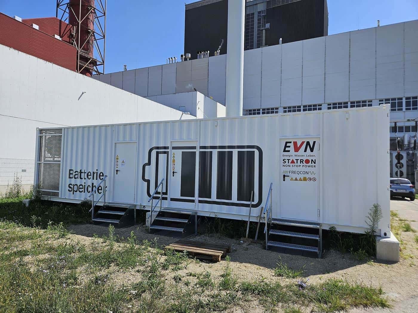 A container-sized battery energy storage system beside an industrial building