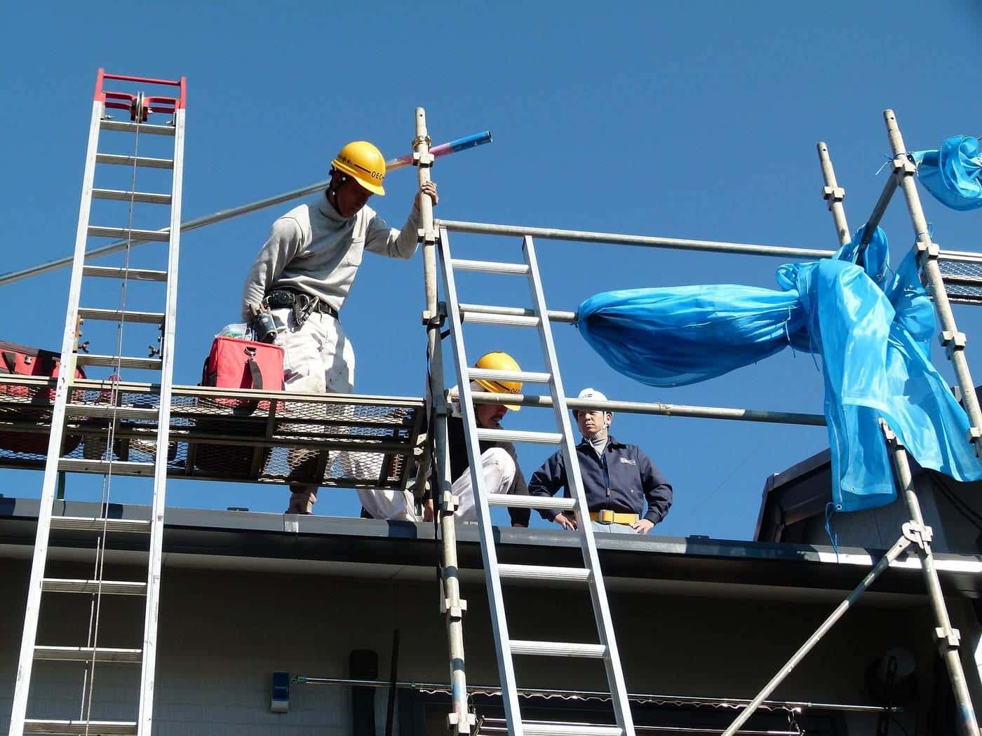 Installers on scaffolding fitting solar panels to a roof